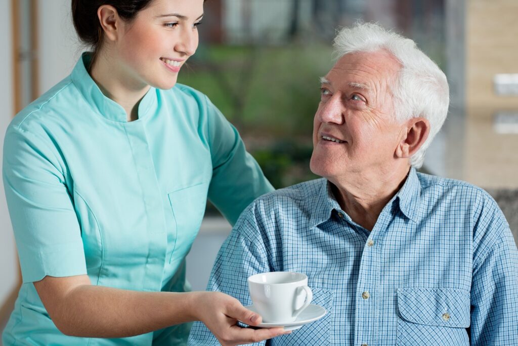 Carer with client chatting and delivering tea. Visiting Home Care Leeds