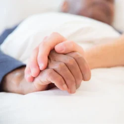 Personal Care Specialists holding client hand on bed